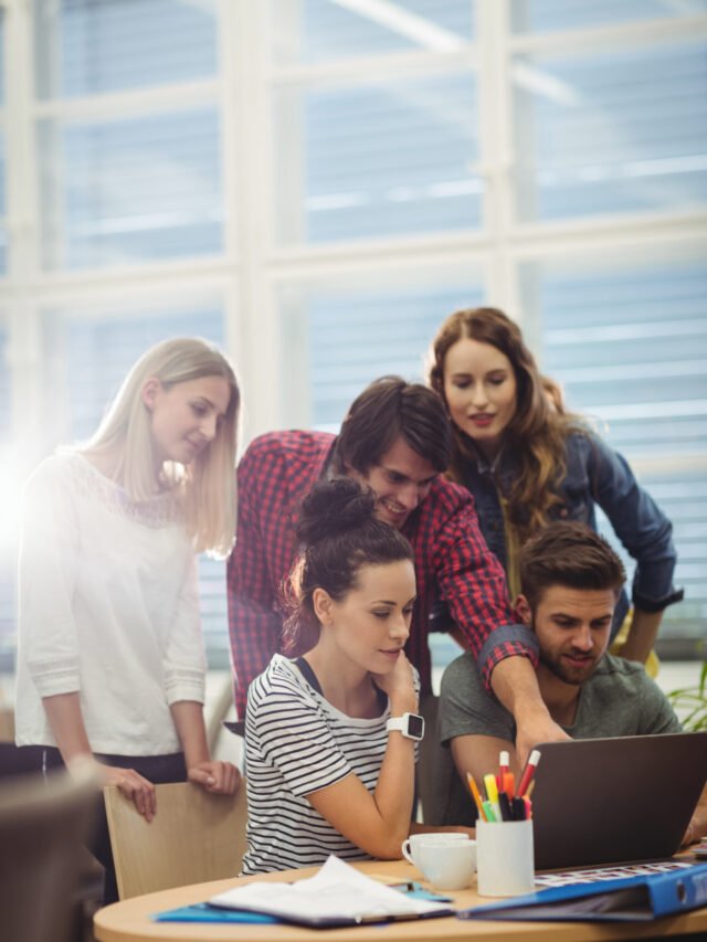 Group of business executives discussing over laptop at their desk